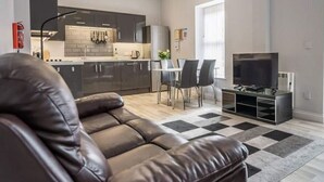 A modern living room with leather sofas, a dining area, and a kitchen. - Vectis Holiday Homes, Modern, spacious apartment, great location, EV Charging (Shanklin)