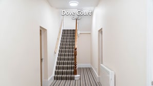 A hallway with a staircase leading to a door labeled "Dove Court Cedar." - Vectis Holiday Homes, Modern, spacious apartment, great location, EV Charging (Shanklin)