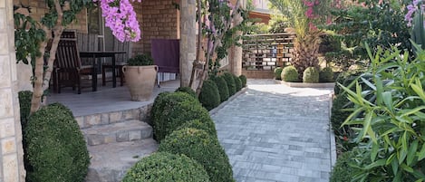 A patio area with a stone pathway, potted plants, and a seating area with a table and chairs.