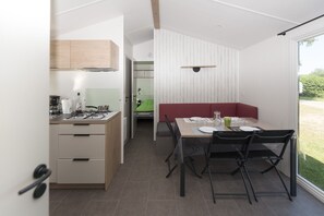 Cozinha moderna com área de refeições, um banco embutido e vista para um jardim verde.