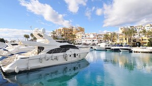 A marina with several yachts docked, surrounded by buildings with Mediterranean architecture. - Guest favorite! Family apartment, terrace, spectacular views & pool near sea (Mijas costa)