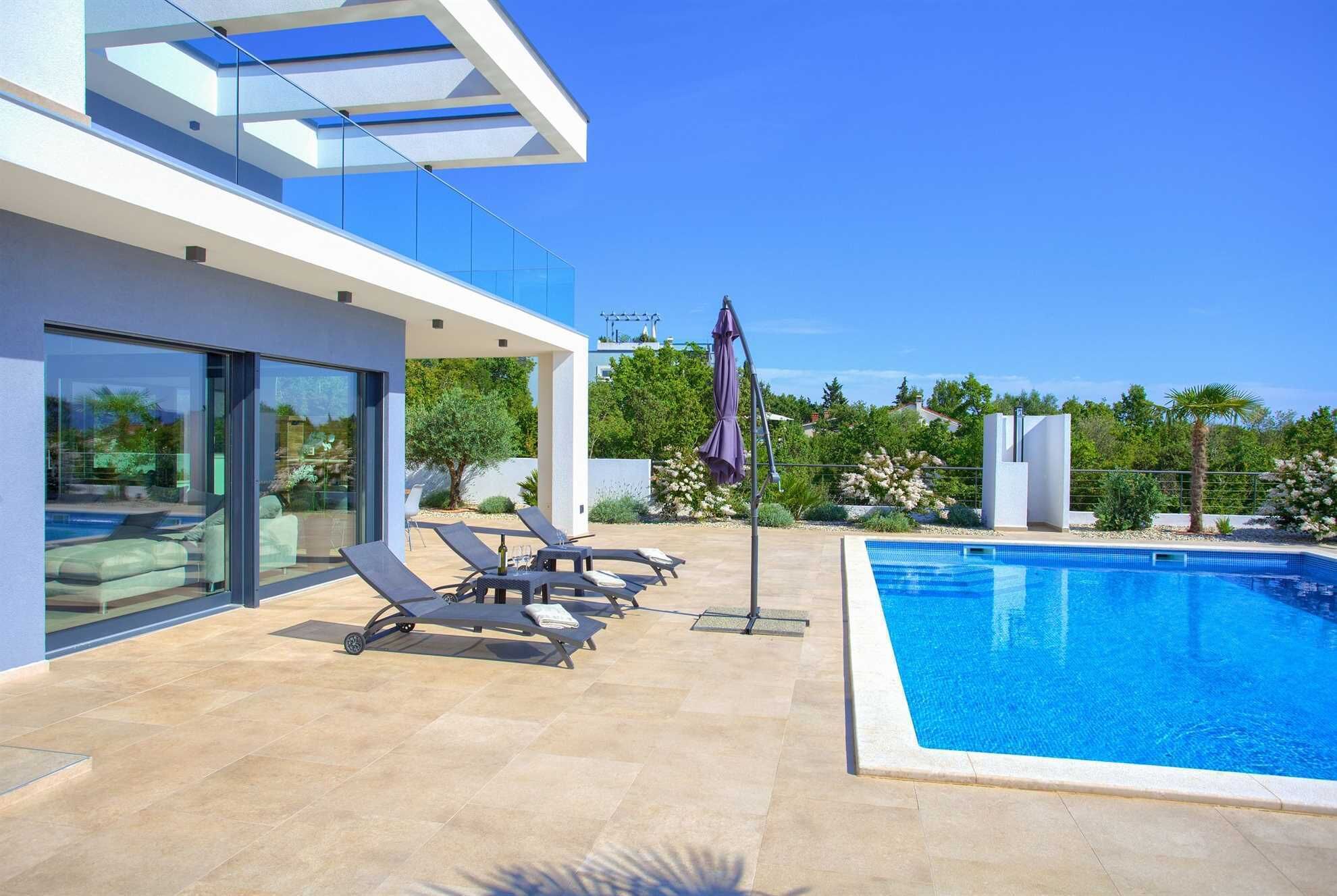A modern outdoor pool area with lounge chairs and a glass-enclosed building.