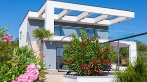 A modern two-story house with a glass facade, a covered outdoor area, and a staircase leading to the entrance. - Villa QUADRA with heated pool (Pinezići)