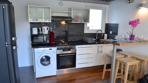 A compact kitchen with a washing machine, microwave, and coffee maker. - Quiet 2 bedrooms apartment (Biarritz)