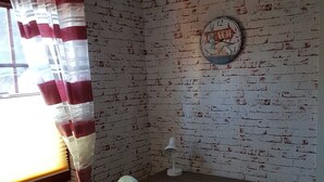 A room with a brick-patterned wall, a wooden desk with a lamp, a chair, and a radiator.