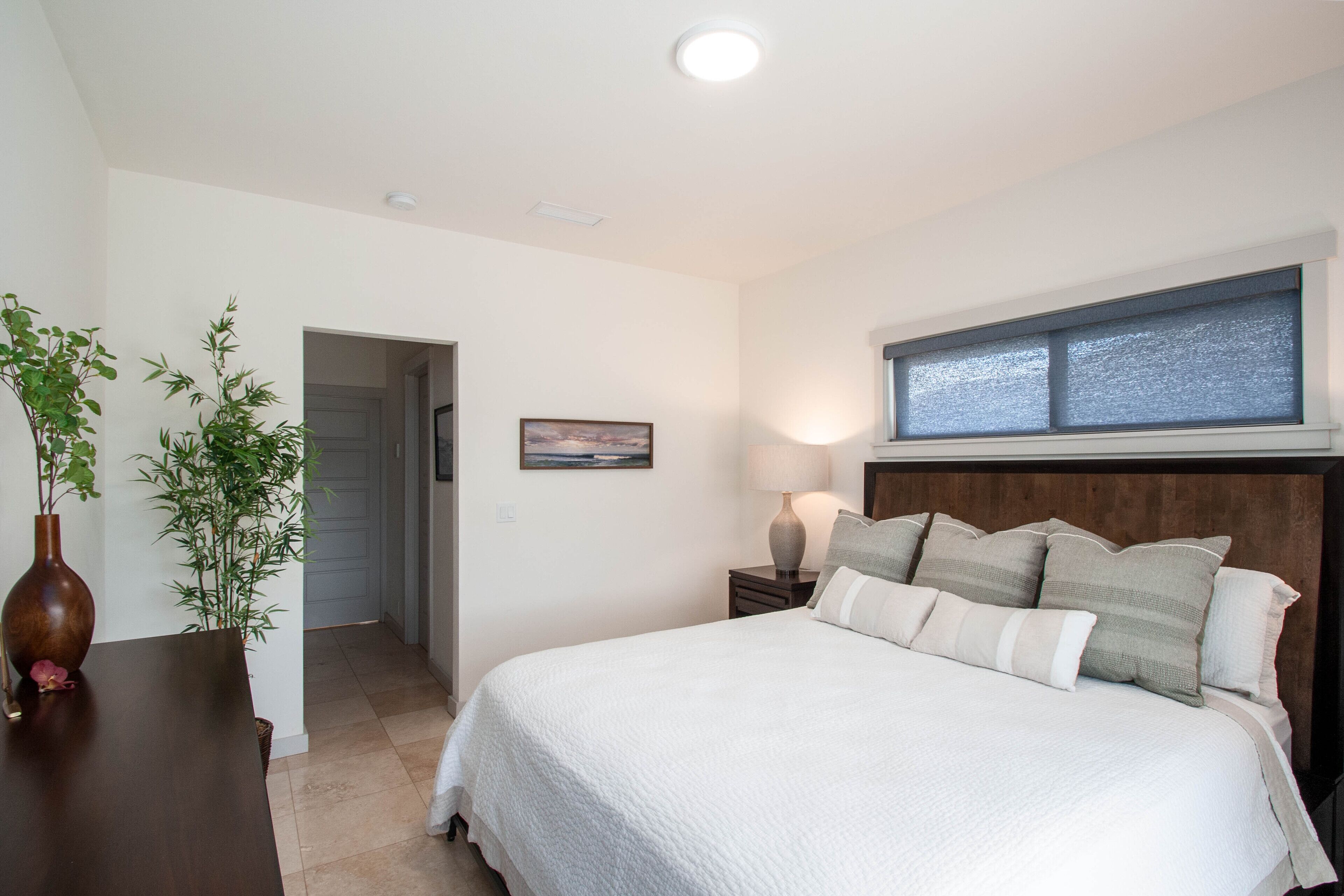 Un dormitorio con una cama grande, mesitas de noche y una puerta que da a otra habitación.