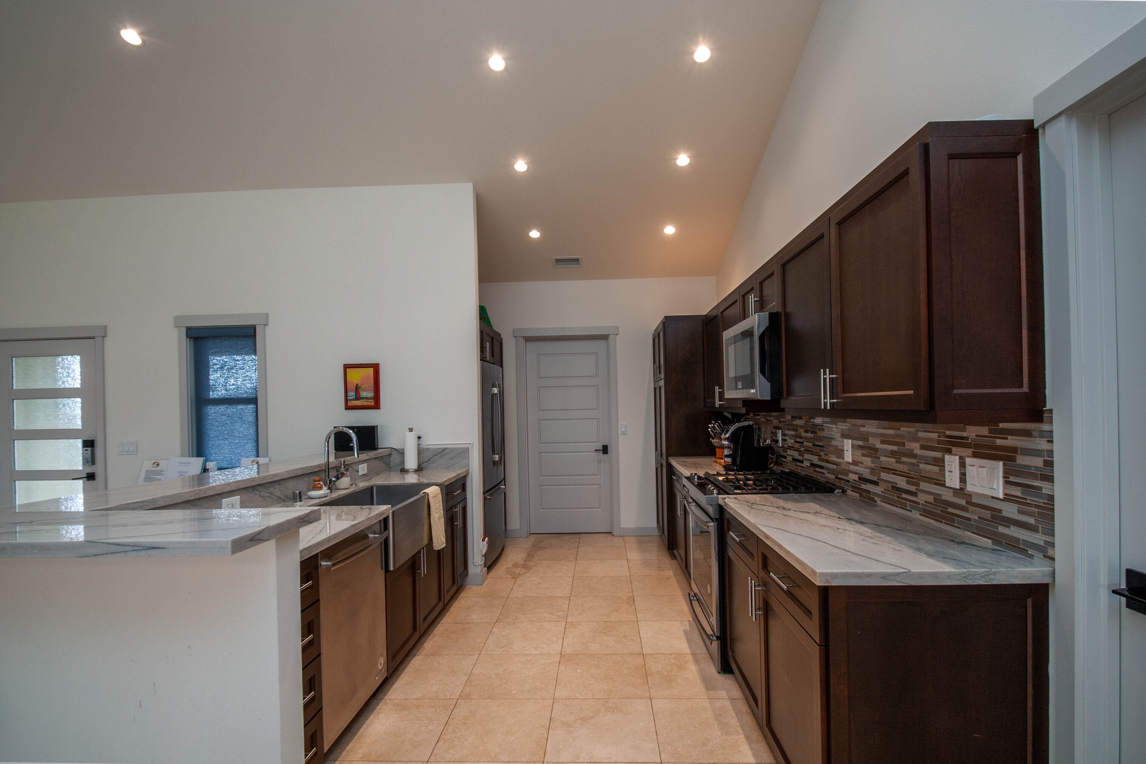 A modern kitchen with a central island, dark wooden cabinets, and a tiled backsplash.