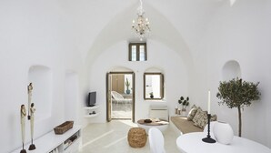 Un salon spacieux doté d’un haut plafond en arc, d’un lustre, d’un ensemble de canapés, d’une table basse et d’un téléviseur.