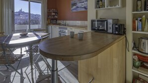 Une cuisine moderne avec un îlot central en bois, des armoires blanches et une vue sur le paysage urbain.