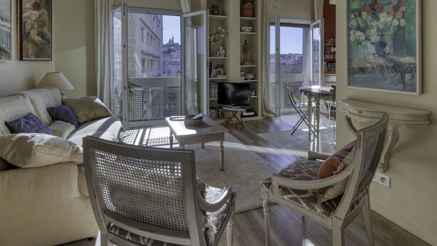 Un salon spacieux comprenant un canapé, un fauteuil, un téléviseur et un balcon offrant une vue sur la ville.
