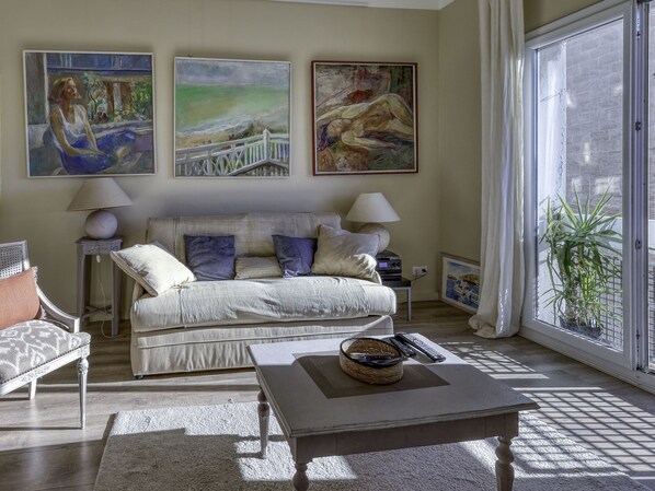 Een woonkamer met een bank, fauteuils, een salontafel en kunstwerken aan de muur.