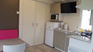 Cocina compacta con refrigerador, microondas y estufa. Cuenta con un comedor con mesa y sillas.