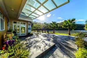A covered outdoor area with a stone pathway leading to a building entrance, surrounded by lush greenery and a view of a lake. - Garden Villa double RM (Yilan County)