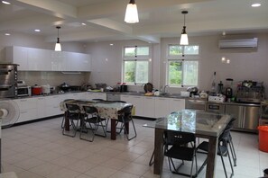 A modern kitchen with white cabinets, a dining area with a glass table, and a large window providing natural light. - Garden Villa double RM (Yilan County)