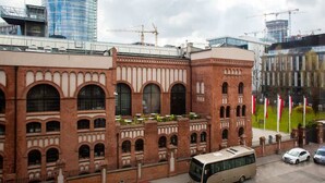 A historic building with arched windows and a brick facade, adjacent to modern high-rise buildings under construction. - Modern Apartment with Air Conditioning | 2 Bedrooms | Parking (Warszawa)
