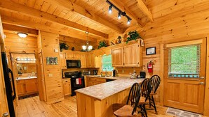 L’intérieur d’un chalet en bois comprend une cuisine, un coin repas et une porte dotée d’une fenêtre.