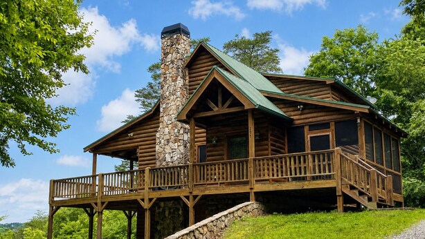 Une cabane en rondins avec une cheminée en pierre, un balcon et un escalier en pierre.