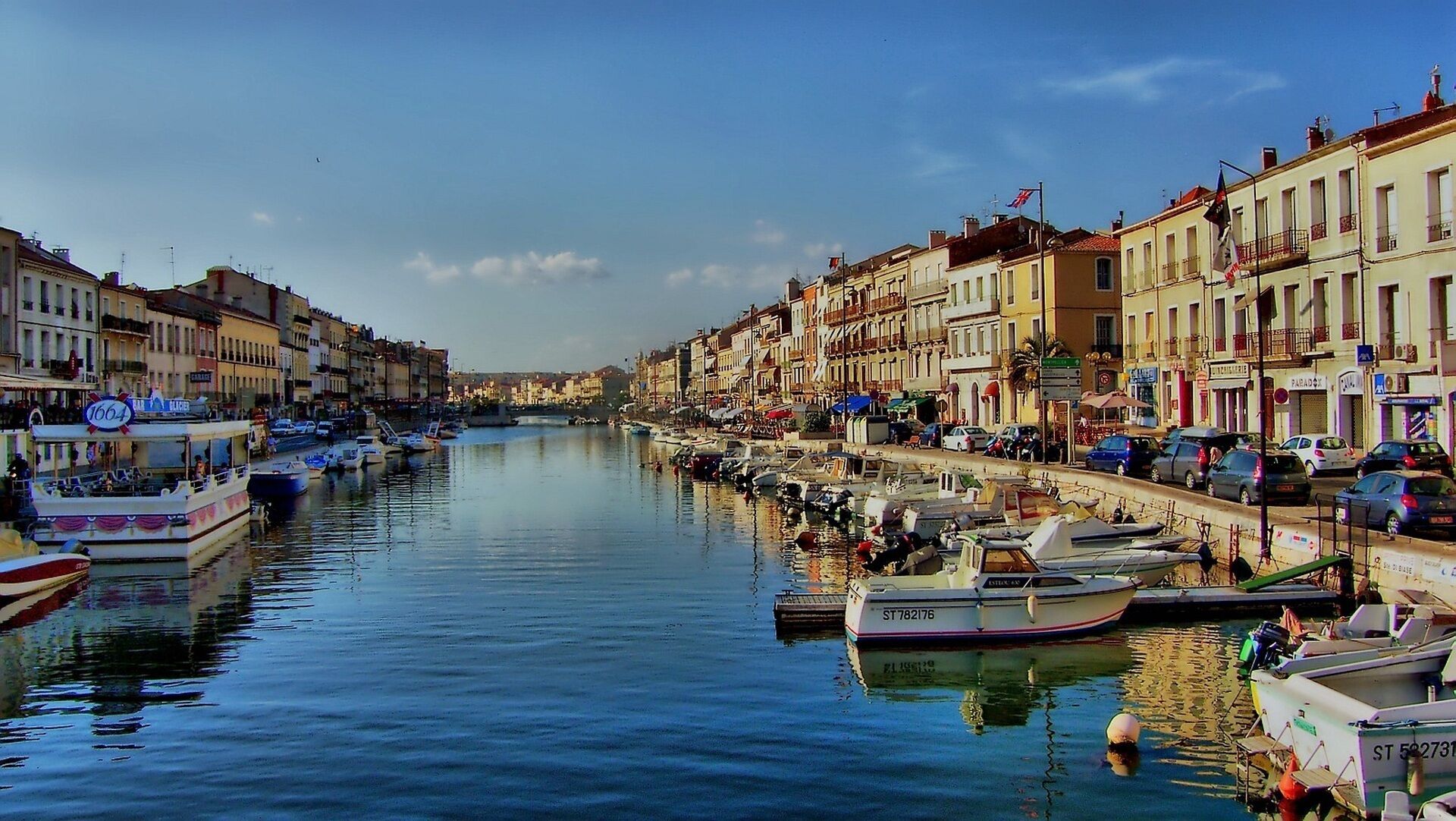 A canal lined with buildings, boats docked along the water, and a clear sky.