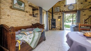 A cozy room with a stone wall, a wooden bed, a fireplace, and a dining area with a table set for two. - Casalle, comfortable restored holiday home with private swimming pool (Montcléra)