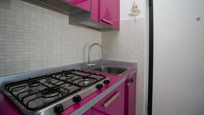 A kitchen with pink cabinets, a gas stove, and a stainless steel sink. - M247 - Marcelli, new two-room apartment with terrace and garage (Marcelli)