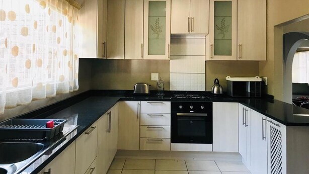 Een keuken met lichte kastjes, een zwart aanrecht, een fornuis en een spoelbak.