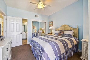 A bedroom with a bed, a dresser, a ceiling fan, and a door leading to another room. - Stunning West End View, Spring/Summer open, book your getaway now! (Panama City Beach)