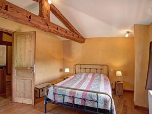Une chambre avec un plafond en bois, un cadre de lit en métal et deux lampes de chevet.