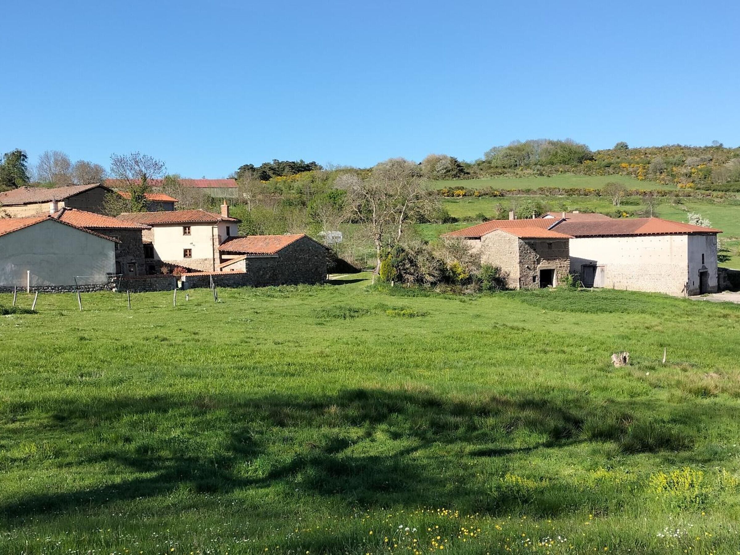 A rural setting with stone buildings and a grassy field.