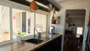 A kitchen with a wooden countertop, a sink, and a coffee machine. There is a window with a view of plants outside. - Charming village house in the Luberon (Cadenet)