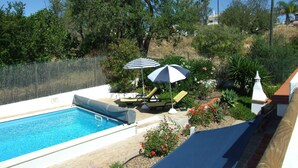 A backyard with a swimming pool, two lounge chairs, and two umbrellas. - Villa, Air-conditioned,  Heated Pool, Peaceful Location.
Beds 3,Bathrooms 3 (Quelfes. Olhao)