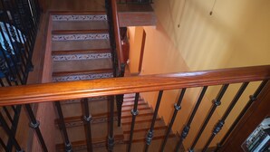 A wooden staircase with patterned tiles, a black metal railing, and a bookshelf with books. - The House of happiness (Alicante)