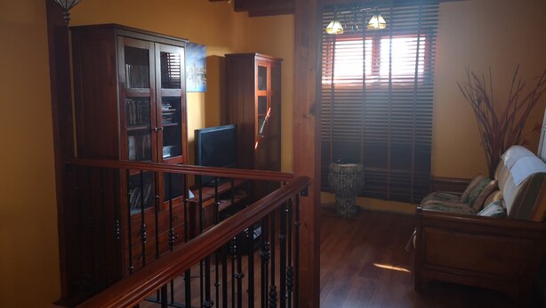 A living room with a wooden staircase, a television, a bookshelf, and a sofa. - The House of happiness (Alicante)