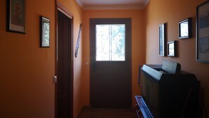 A hallway with orange walls, a wooden door, and a window with decorative ironwork. - The House of happiness (Alicante)