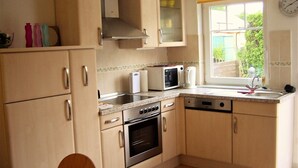 A compact kitchen with a stove, oven, microwave, and sink.