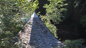 A small stone building with a pointed roof, a window, and a metal gate. - Gite on the edge of the Arac in a green setting with swimming pool (Aleu)
