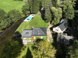 An aerial view of a property with a swimming pool, a large lawn, and a river.