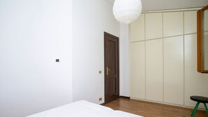 Quarto com cama, guarda-roupa, cadeira e luminária pendente.