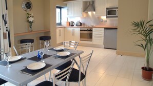 A modern kitchen with white cabinets, a stainless steel range hood, and a microwave. - Cuirt na Coiribe 4 bedroom Apartment (sleeps 5) (Galway)