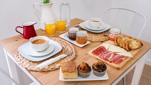 Una mesa de desayuno con café, jugo, pasteles y queso.