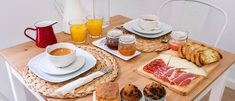 A breakfast table with coffee, juice, pastries, and cheese.