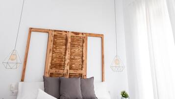 A bedroom with a wooden ceiling, a bed with grey bedding, and a hanging light fixture.