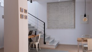 Un interior moderno con una escalera, un escritorio con una computadora y un comedor.