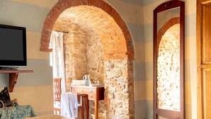 A room with a brick fireplace, a wooden dresser, a television, and a bed with patterned bedding. - Beautiful private villa for 20 people with WIFI, private pool, sauna, TV and panoramic view (Rapale)