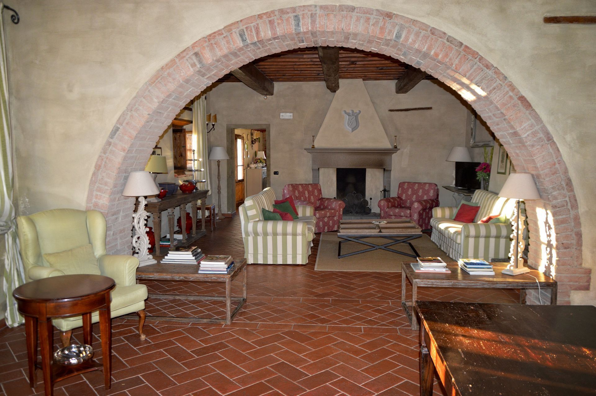 Una sala acogedora con chimenea, sofás a rayas y un arco de ladrillo.