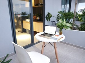 A modern balcony with a laptop, a book, and a potted plant.