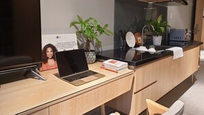 A modern kitchen with a laptop on a wooden desk, a television, and a potted plant. - Tripporo - Homestay (Ho Chi Minh City)