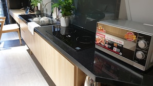 A modern kitchen with a black countertop, stainless steel appliances, and a box of Sharp brand food processor. - Tripporo - Homestay (Ho Chi Minh City)