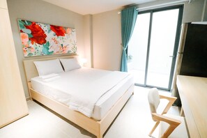 A neatly made bed with white linens, a wooden headboard, and a floral artwork above it.