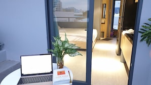 A hotel room with a laptop on a small table, a plant, and a book titled "Chia Khoa." - Tripporo - Homestay (Ho Chi Minh City)