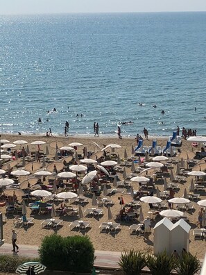 A beach with numerous umbrellas and sun loungers, a sandy shore, and the ocean in the background. - Appartement DreamAppart Lido di Jesolo Venise (Lido di Jesolo)